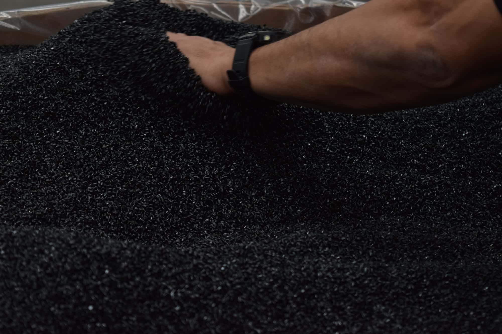 Mano de un operador de PIMSA entre pellet negro recuperado
